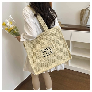 Détail du patch brodé LOVE LIFE sur un grand sac cabas en paille au style bohème