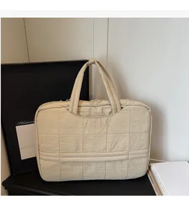 Detail view of beige quilted laptop bag with grid texture, top handle and dual zippers