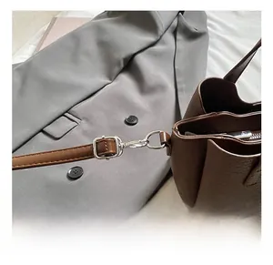 Detail of silver metal hook and adjustable buckle on brown pebbled leather shoulder bag