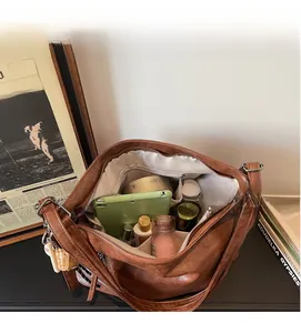 Detailed interior of vintage brown shoulder bag showing large capacity and multi-layer pockets