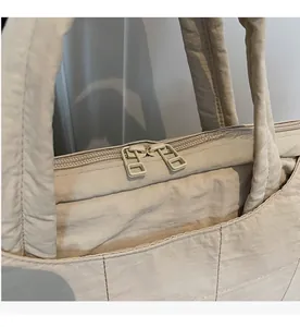 Detail of smooth dual-zipper closure on a beige quilted laptop tote bag