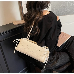 Détail du sac baguette blanc cassé avec motifs d'étoiles et nœuds décoratifs latéraux