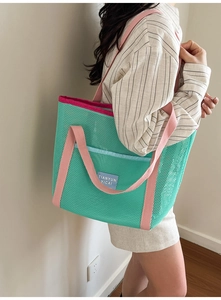 Détail du sac cabas en mesh vert avec anses roses et poche bleue sur l'épaule
