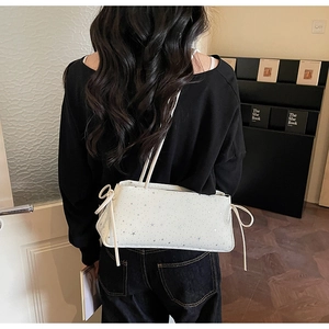 Détail du sac baguette blanc avec étoiles argentées et nœuds décoratifs à cordon