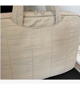 Detailed view of quilted beige laptop bag with soft fabric texture and sturdy top handle