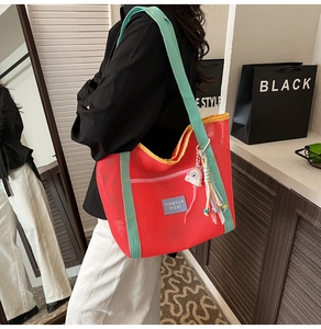 Détail du sac cabas en maille avec pompon arc-en-ciel et bordures contrastées orange