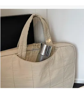 Detailed close-up of a quilted laptop bag with a spacious pocket holding a water bottle