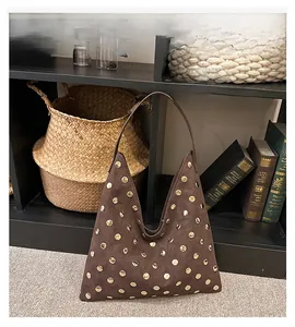 Detail of dark brown matte tote bag with polished golden stud rivets in hobo style