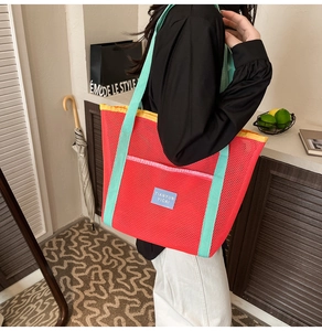 Détail du sac cabas en maille rouge avec anses vert menthe et liseré jaune contrastant