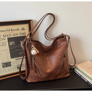 Detail of vintage brown PU leather tote bag with functional zippers and sports charm