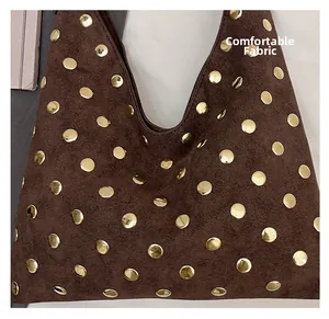Close-up of soft brown suede tote bag with decorative vintage golden metal rivets detail