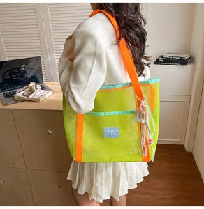 Détail du sac cabas en maille vert néon avec anses orange vif et pompon arc-en-ciel