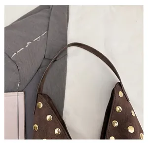 Detailed close-up of retro brown suede tote bag featuring decorative gold metal rivets