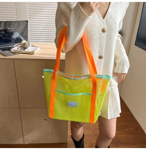 Détail du sac cabas en maille vert néon avec anses oranges et étiquette bleue de marque