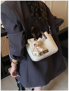 Detailed view of the textured lychee leather hand bag with a cute plush rabbit charm