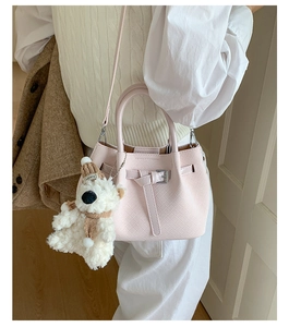 Detail of pink woven bucket bag featuring silver buckle and cute plush bear accessory
