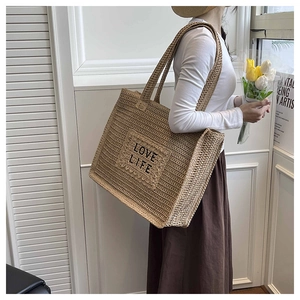 Détail de la broderie LOVE LIFE sur un grand sac cabas en paille tissée beige