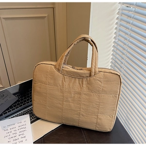 Close-up of a khaki quilted laptop bag with a rectangular pattern and top handles