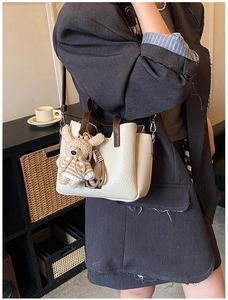 Detail view of cream white pebbled leather handbag featuring a cute plush bunny charm