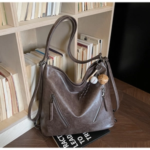 Detail view of brown vintage hobo bag texture and zipper pockets against books