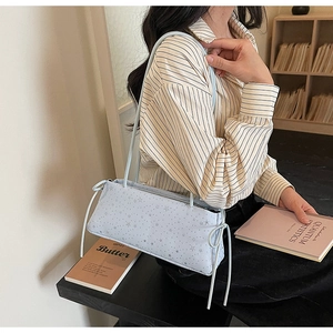 Détail du sac baguette bleu clair avec motifs étoiles et nœuds décoratifs sur le côté