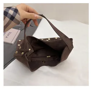 Detail view of brown suede tote bag interior with magnetic snap and metal rivet accents