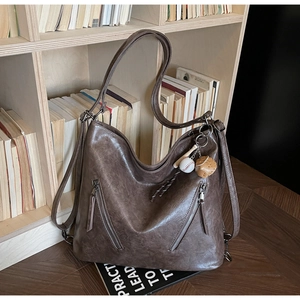 Detail view of vintage brown tote bag with leather texture and baseball glove charm accessory
