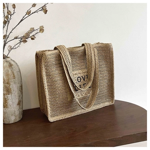 Gros plan sur la texture crochetée et la broderie LOVE LIFE du sac en paille
