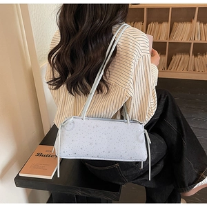 Détail du sac baguette bleu clair avec motifs d'étoiles argentées et cordons à longs glands