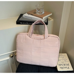 Detail of light pink quilted laptop bag with soft padded texture and comfortable handle