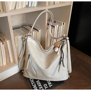 Close-up of beige vintage faux leather tote bag with functional zippers and baseball charm