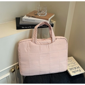 Detail of light pink quilted laptop bag with reinforced handles and soft cotton texture