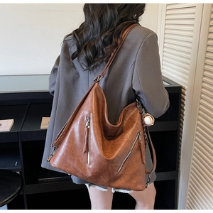 Detail view of vintage brown leather tote bag with functional dual front metal zippers