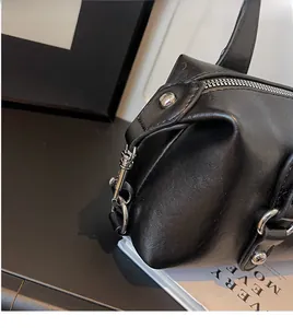Detailansicht des silbernen Metallhakens und der strukturierten schwarzen Ledertasche