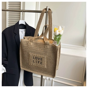 Détail du sac cabas en paille tissée avec broderie LOVE LIFE noire et poignées d'épaule solides
