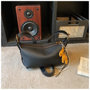 Détail du sac bandoulière en cuir grainé noir avec pendentif cheval jaune élégant