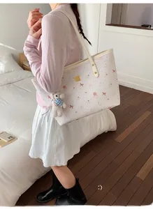 Détail d'un sac cabas beige avec motifs d'ours roses et pendentif en peluche doux