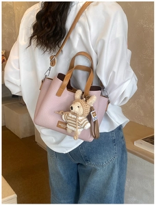 Detail of pink pebbled leather handbag with contrast brown straps and cute knitted rabbit charm