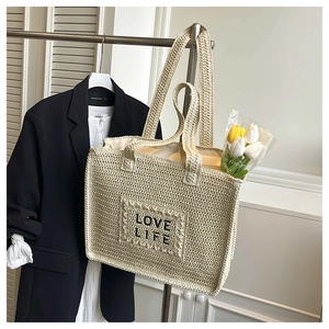 Détail du sac cabas en paille beige avec broderie LOVE LIFE et texture crochetée ajourée