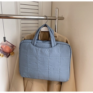Quilted blue laptop bag in nylon fabric with top handles shown in a lifestyle setting