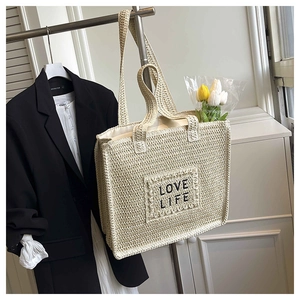 Détail du sac fourre-tout en paille tissée avec broderie noire LOVE LIFE et anses en corde