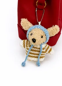 Nahaufnahme eines niedlichen Plüschhund-Anhängers in Streifenpullover an roter Tasche