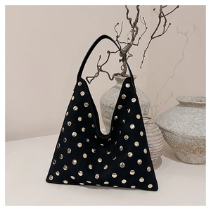 Detail of black suede tote bag with golden rivets against a minimalist background