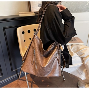 Detail view of large vintage dark brown leather shoulder bag with decorative zippers