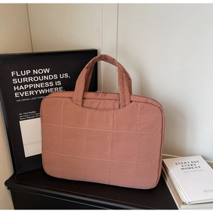 Close-up of pink quilted laptop bag with double zippers and sturdy handles for protection