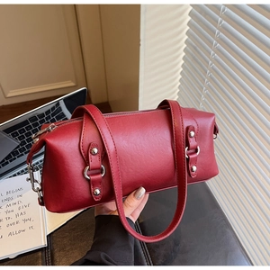 Detailansicht der tiefroten zylindrischen Ledertasche mit silbernen Ringbeschlägen