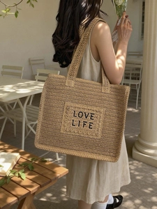 Sac cabas en paille avec broderie Love Life dans un café en plein air ensoleillé