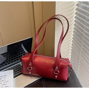 Dunkelrote Zylindertasche aus Leder mit silbernen Nieten auf einem Schreibtisch