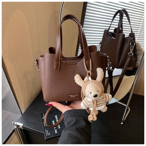Close-up of litchi grain texture on the brown tote bag with cute bear charm and logo