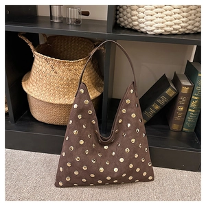 Detailed macro view of brown suede tote bag featuring polished gold stud embellishments